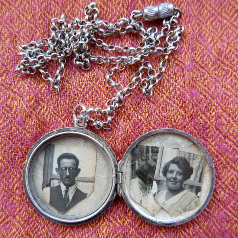 Image of a silver locket, with three black and white photographs in it.